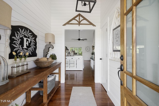 entrance foyer with dark wood-style flooring and wood walls