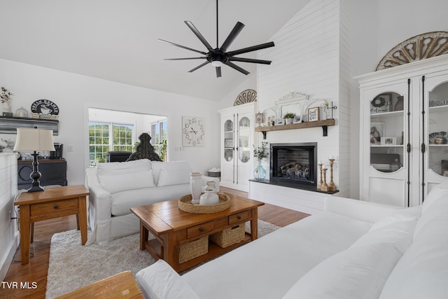 living area featuring a ceiling fan, high vaulted ceiling, wood finished floors, and a fireplace
