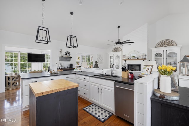 kitchen with dark wood-style flooring, a kitchen island, a sink, wood counters, and dishwasher