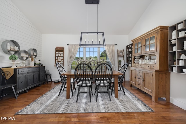 dining room with high vaulted ceiling, an inviting chandelier, and wood finished floors