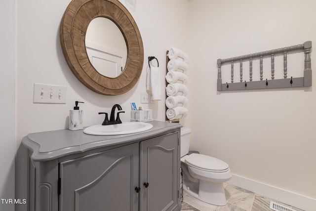half bathroom featuring vanity, visible vents, marble finish floor, toilet, and baseboards