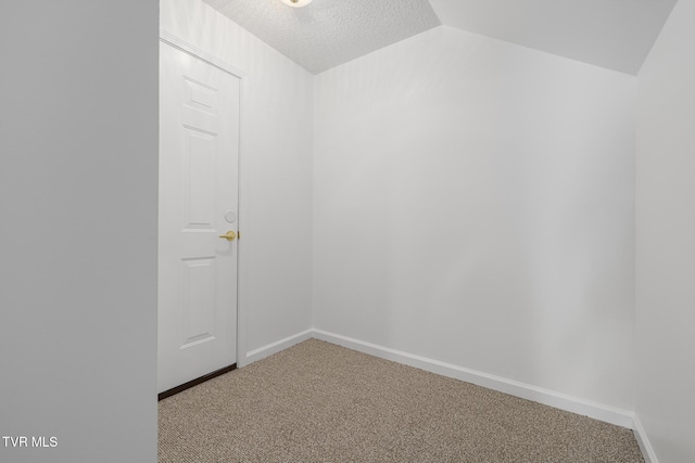 empty room with carpet floors, baseboards, vaulted ceiling, and a textured ceiling