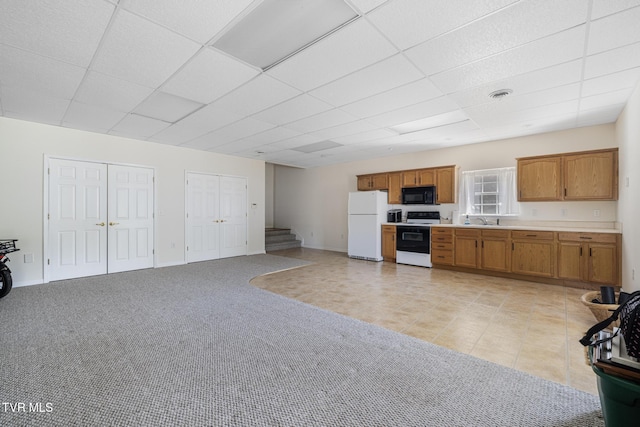 kitchen featuring electric range, black microwave, a sink, a paneled ceiling, and freestanding refrigerator