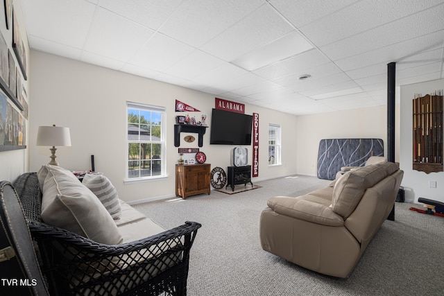carpeted living area featuring baseboards and a paneled ceiling