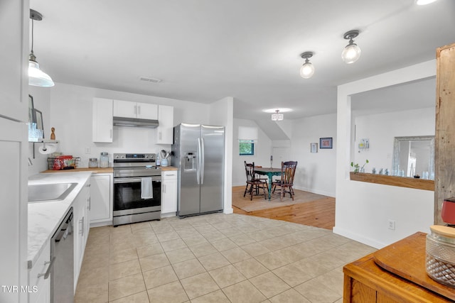 302 Wilson Ave, Johnson City, TN 37604 - kitchen with appliances with stainless steel finishes, light countertops, light tile patterned flooring, under cabinet range hood, and white cabinetry