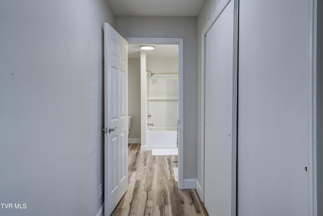 hall with light wood-type flooring and baseboards