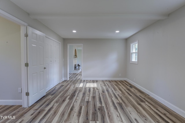 empty room with baseboards, beam ceiling, recessed lighting, and wood finished floors