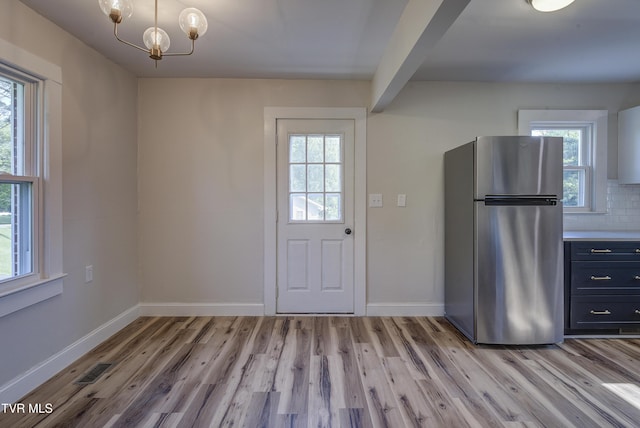 interior space with baseboards, visible vents, light wood-style flooring, and a chandelier