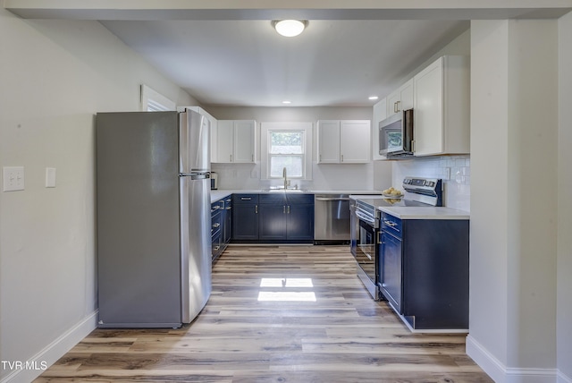 kitchen with stainless steel appliances, blue cabinetry, baseboards, and light wood-type flooring