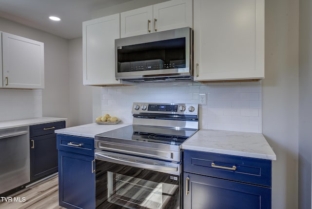 kitchen featuring appliances with stainless steel finishes, blue cabinets, and white cabinetry