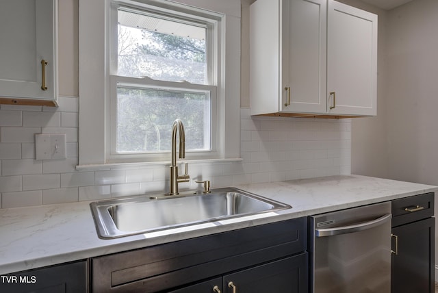 kitchen featuring a sink, white cabinets, backsplash, and dishwasher