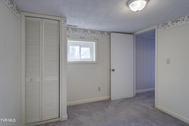 unfurnished bedroom featuring visible vents, a closet, baseboards, a textured ceiling, and carpet flooring