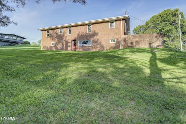 rear view of house featuring a lawn and brick siding
