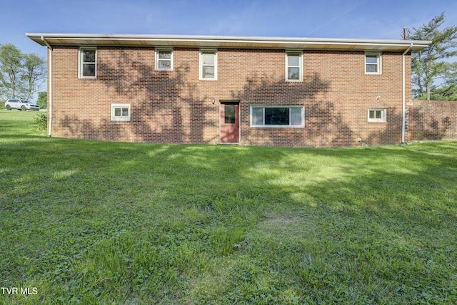 rear view of property featuring a yard and brick siding