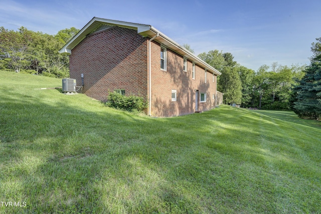 view of side of property featuring a lawn, central AC unit, and brick siding