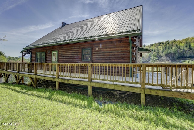 rear view of house with a wooden deck, log exterior, and metal roof