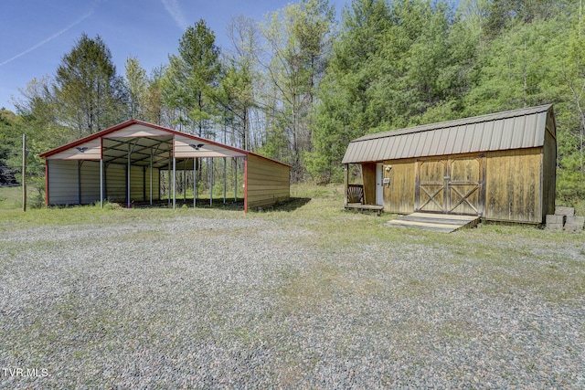 view of yard with a detached carport, an outbuilding, a storage unit, and driveway