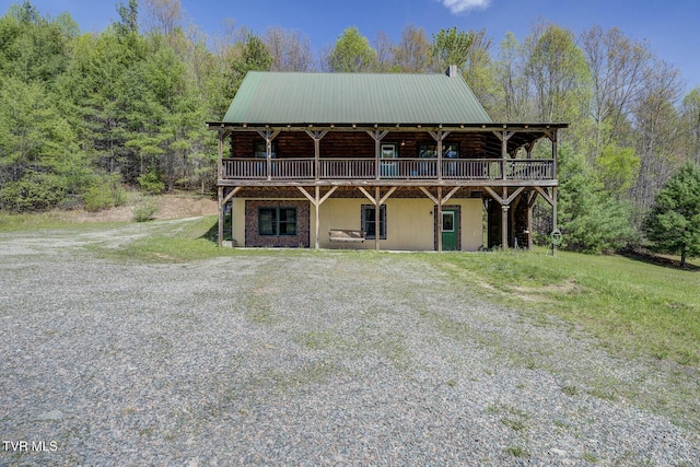view of front of property with a view of trees, a deck, and metal roof