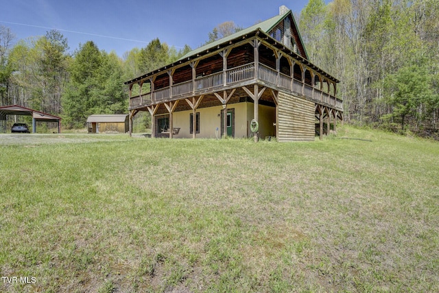 view of front of property with a detached carport, a wooden deck, a view of trees, and a front lawn