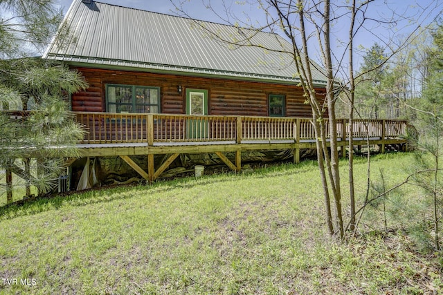 rear view of house featuring a lawn and metal roof