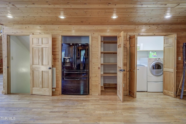 laundry room with wooden walls, laundry area, washing machine and dryer, and light wood-style flooring
