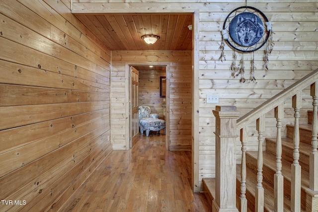 corridor with wooden walls, wood ceiling, wood-type flooring, and stairs