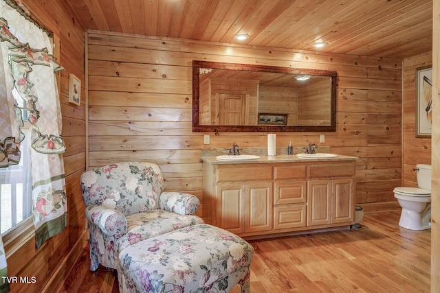 bathroom featuring wooden walls, wood ceiling, toilet, and a sink
