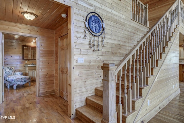 stairs featuring wood ceiling, wood-type flooring, and wood walls