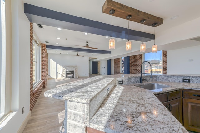 200 E Main St Unit 5, Johnson City, TN 37604 - kitchen with visible vents, a sink, light stone counters, a fireplace with raised hearth, and light wood finished floors
