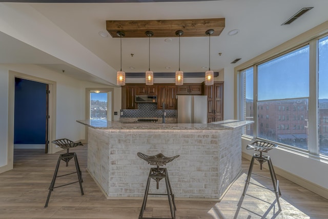 200 E Main St Unit 5, Johnson City, TN 37604 - kitchen featuring visible vents, freestanding refrigerator, decorative backsplash, range hood, and light stone counters