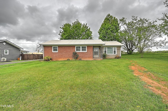 single story home featuring brick siding, fence, metal roof, and a front yard