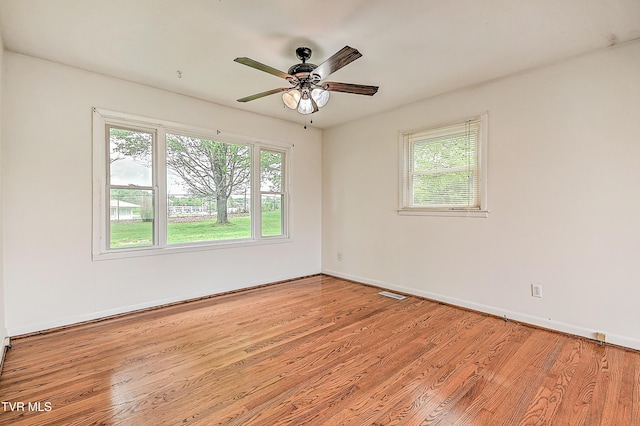 unfurnished room featuring visible vents, light wood-style flooring, ceiling fan, and a wealth of natural light