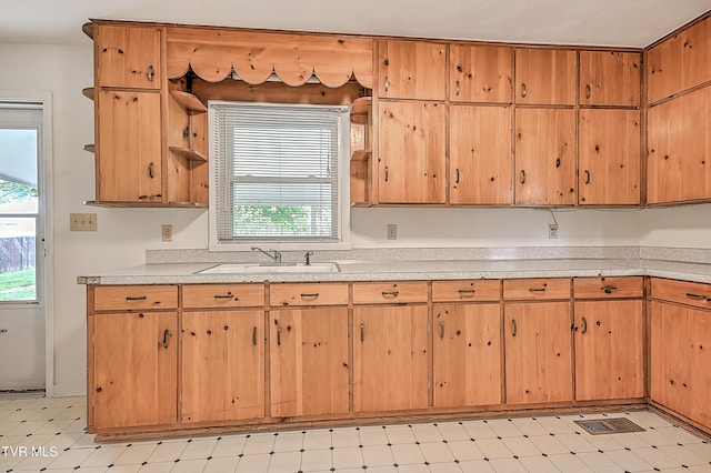 kitchen featuring light countertops, open shelves, a sink, and light floors