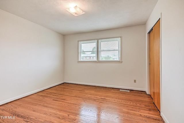 unfurnished bedroom featuring baseboards, visible vents, light wood-style flooring, and a closet
