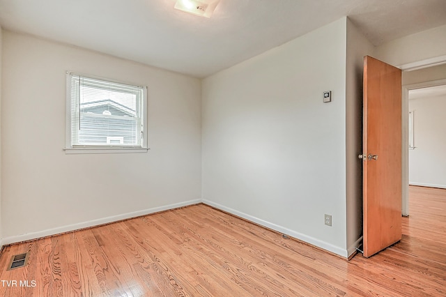 spare room with baseboards, wood finished floors, and visible vents
