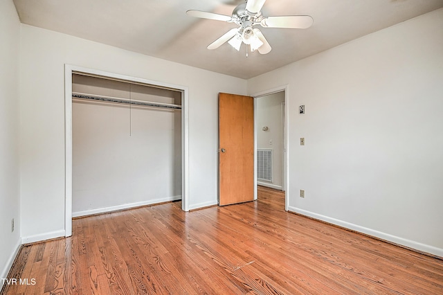 unfurnished bedroom featuring baseboards, a closet, wood finished floors, and visible vents