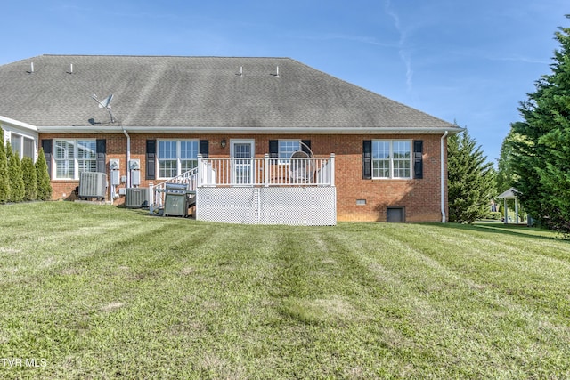 rear view of house with a wooden deck, cooling unit, brick siding, a shingled roof, and a yard
