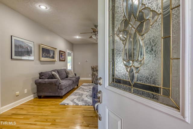entrance foyer featuring a ceiling fan, baseboards, wood finished floors, and a textured ceiling