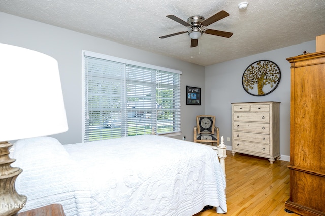 bedroom with a ceiling fan, a textured ceiling, and light wood finished floors