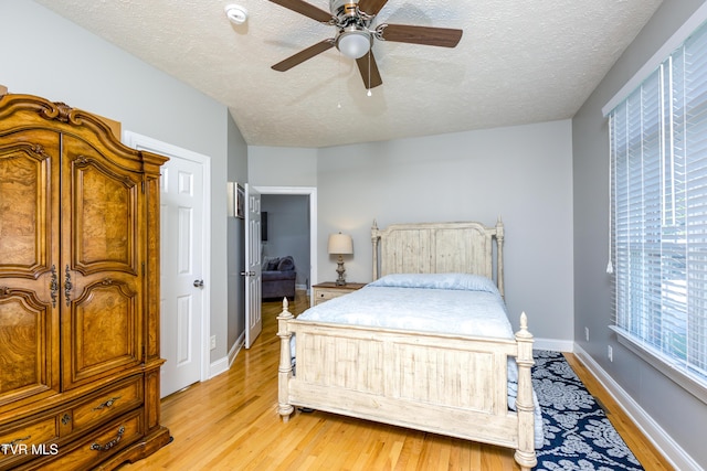 bedroom with baseboards, a textured ceiling, light wood-style flooring, and ceiling fan