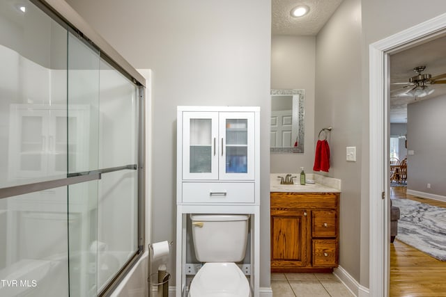 full bathroom with vanity, toilet, a textured ceiling, a ceiling fan, and baseboards