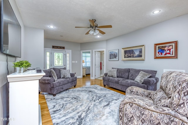 living area featuring recessed lighting, ceiling fan, light wood-type flooring, and a textured ceiling