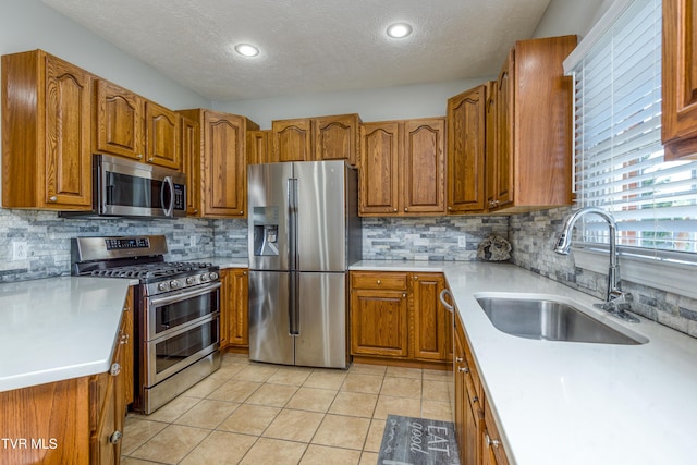 kitchen featuring brown cabinets, appliances with stainless steel finishes, a sink, and light countertops