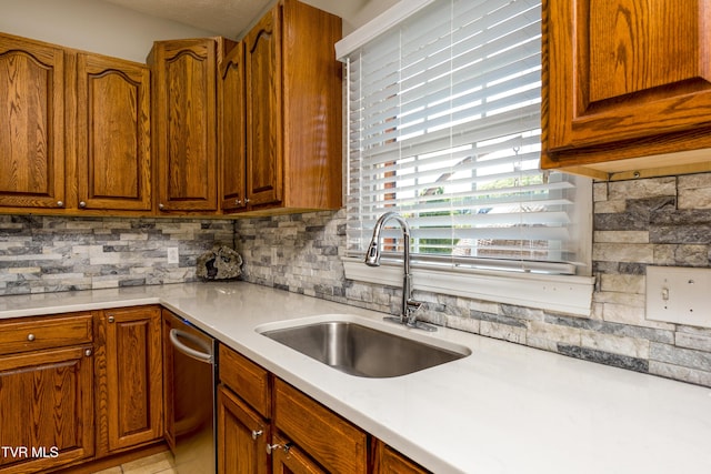 kitchen featuring stainless steel dishwasher, backsplash, a sink, and light countertops