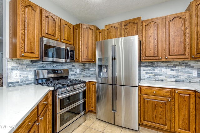 kitchen with brown cabinets, stainless steel appliances, tasteful backsplash, and light countertops