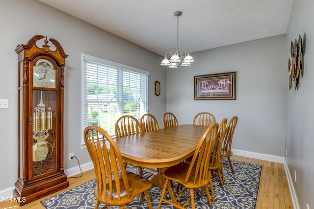 dining space with an inviting chandelier, baseboards, and light wood-type flooring