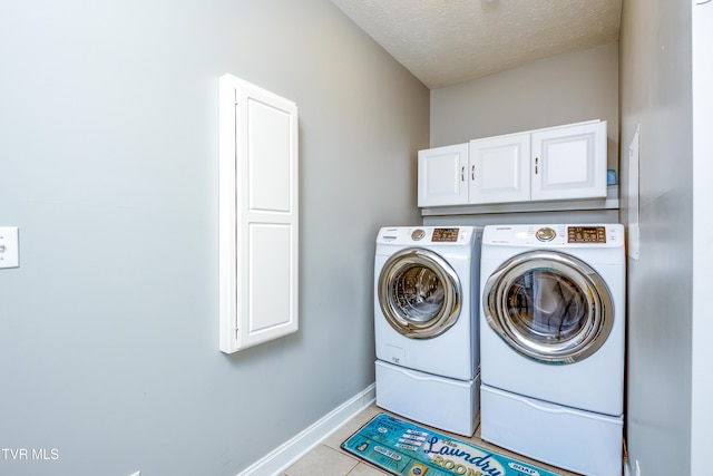 laundry room with cabinet space, tile patterned flooring, separate washer and dryer, a textured ceiling, and baseboards