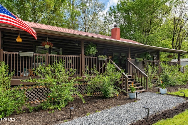 exterior space with a wooden deck, a chimney, and metal roof
