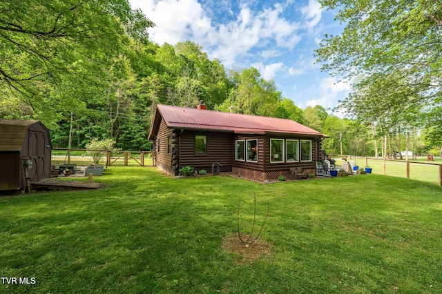 rear view of house featuring fence, a shed, a chimney, log siding, and a lawn