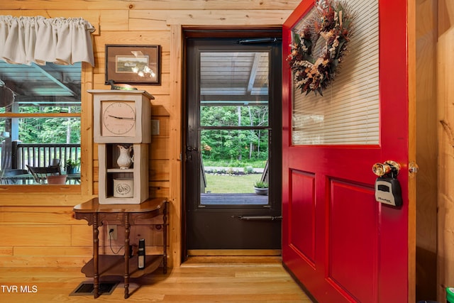 entryway with light wood-type flooring, wooden walls, and visible vents
